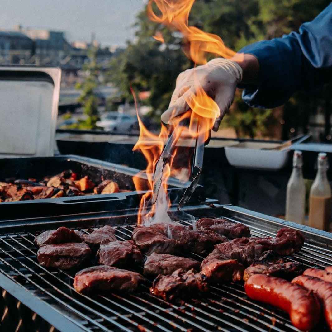 Person grilling meat on a barbecue with flames